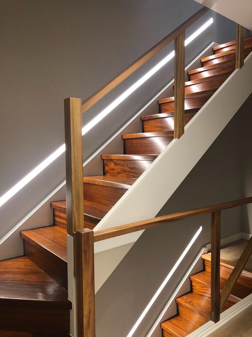 Escalera de madera con luz en el pasamanos