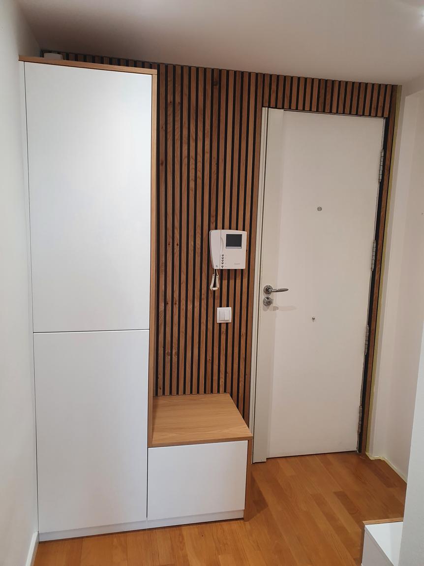 Entrada con armario alto, listones y banco de roble