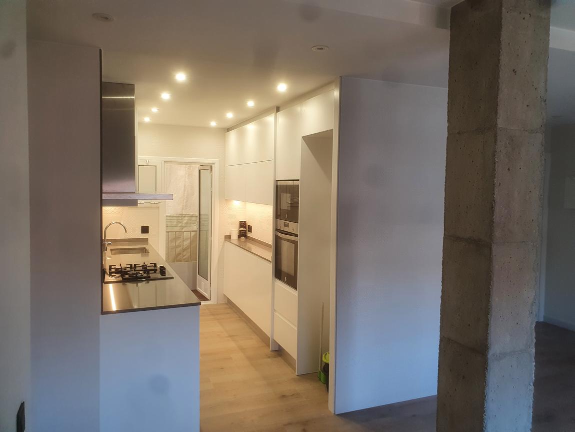 Cocina blanca junto a un pilar de hormigón