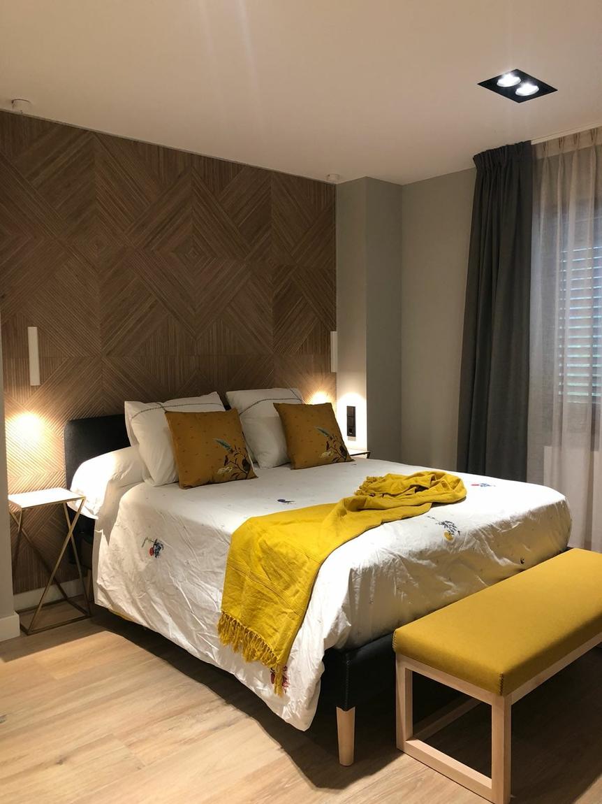 Dormitorio con panel de madera y banco